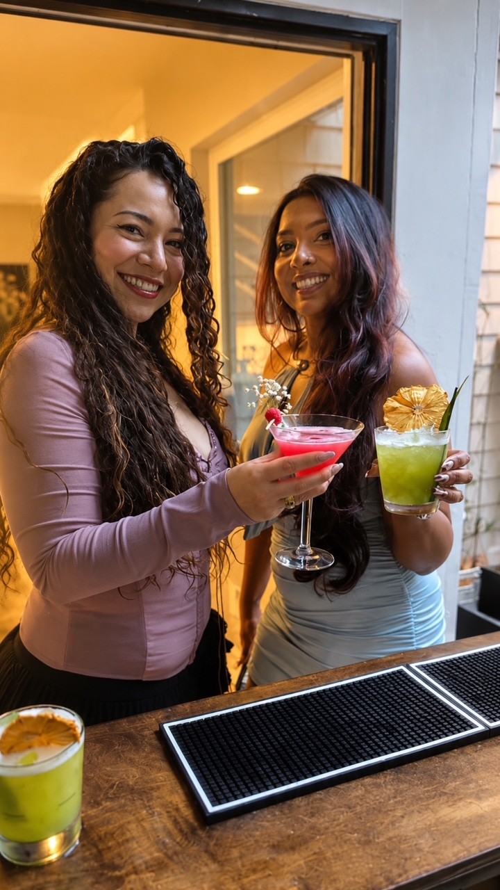 Two guests smiling with colorful signature drinks