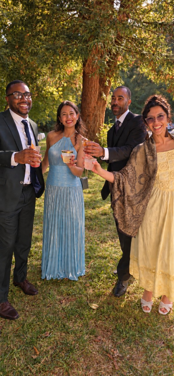 Wedding guests gathered with drinks beneath the trees