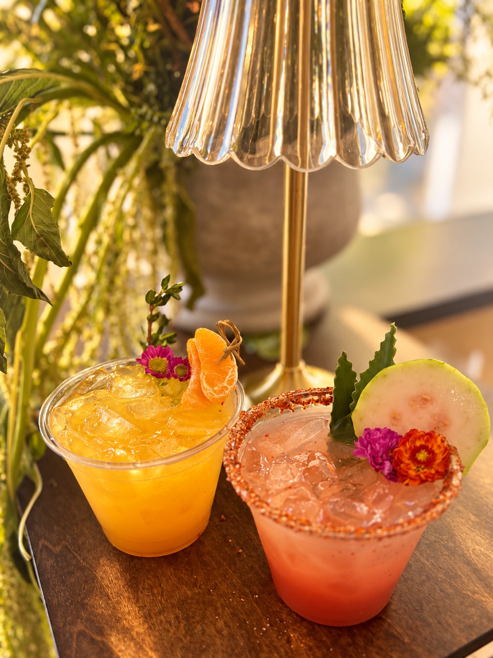 Two garnished cocktails beneath a glass lamp