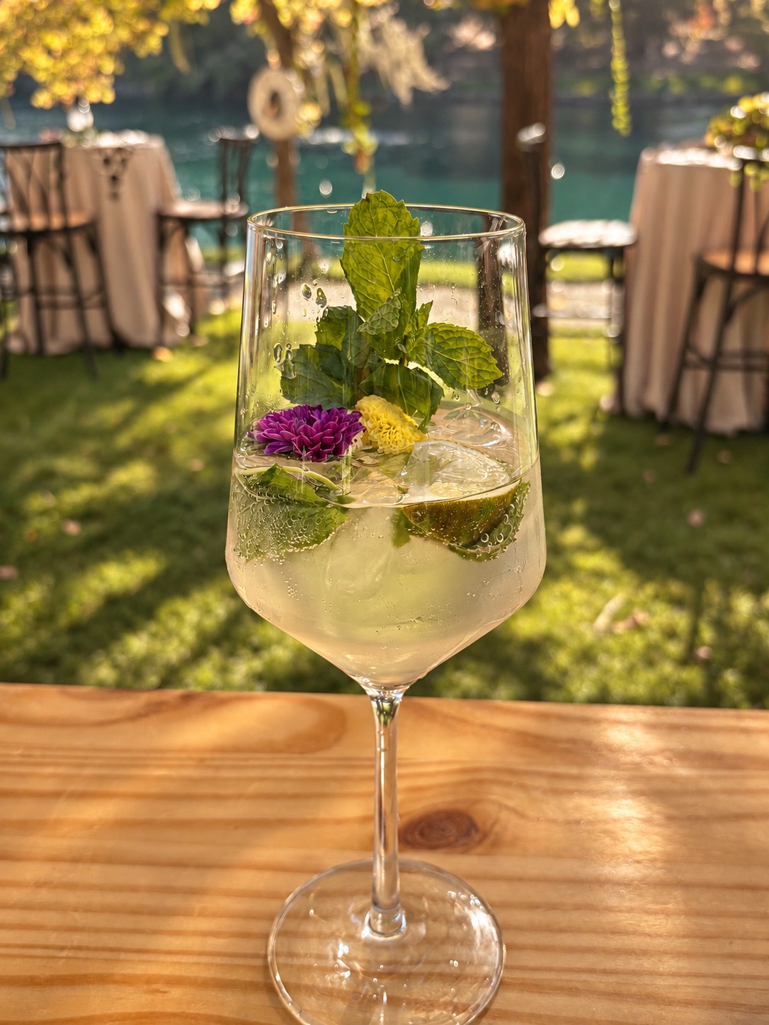A cocktail garnished with mint, lime, and flowers at a garden celebration