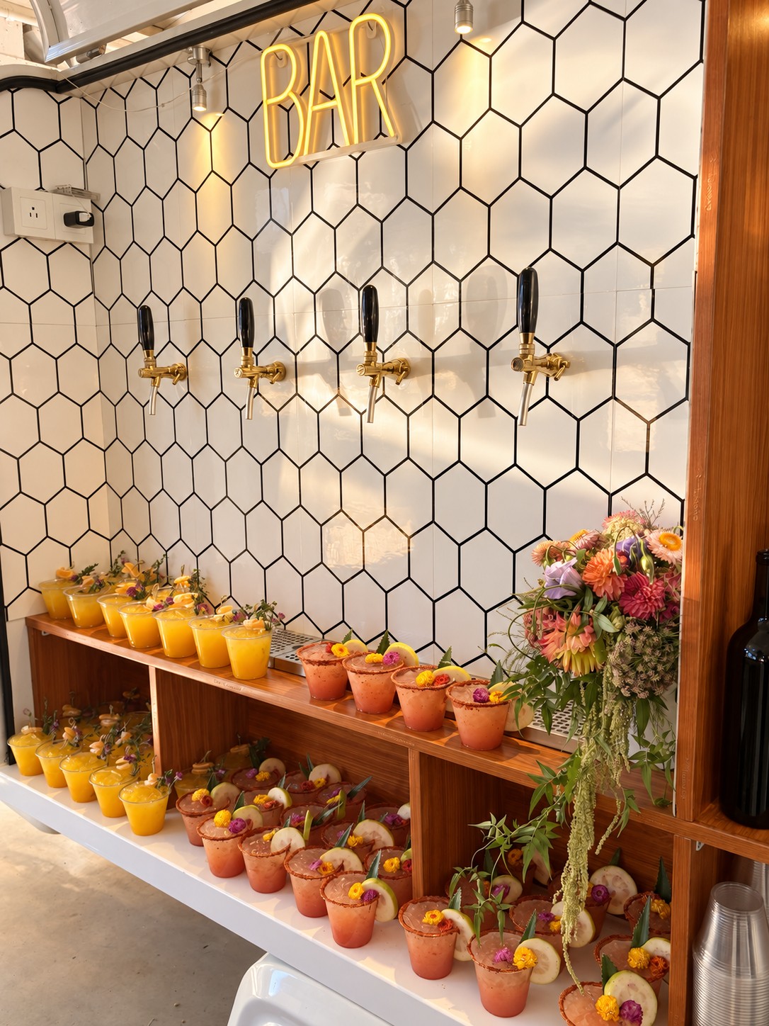 Signature cocktails arranged on the Piaggio shelves beside flowers